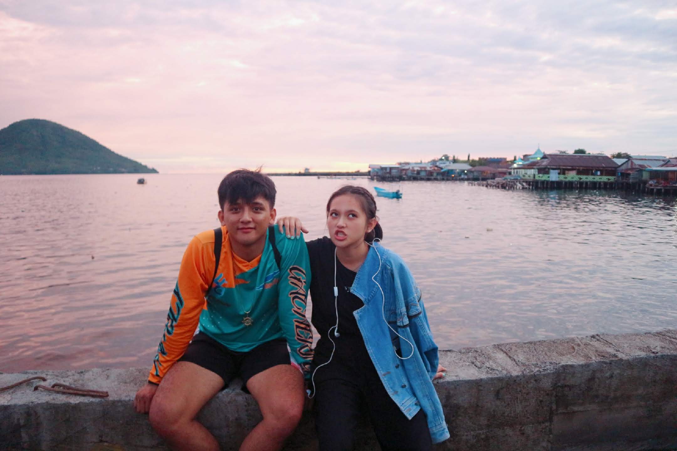 Brenda and Marck sitting together beside the water at sunset
